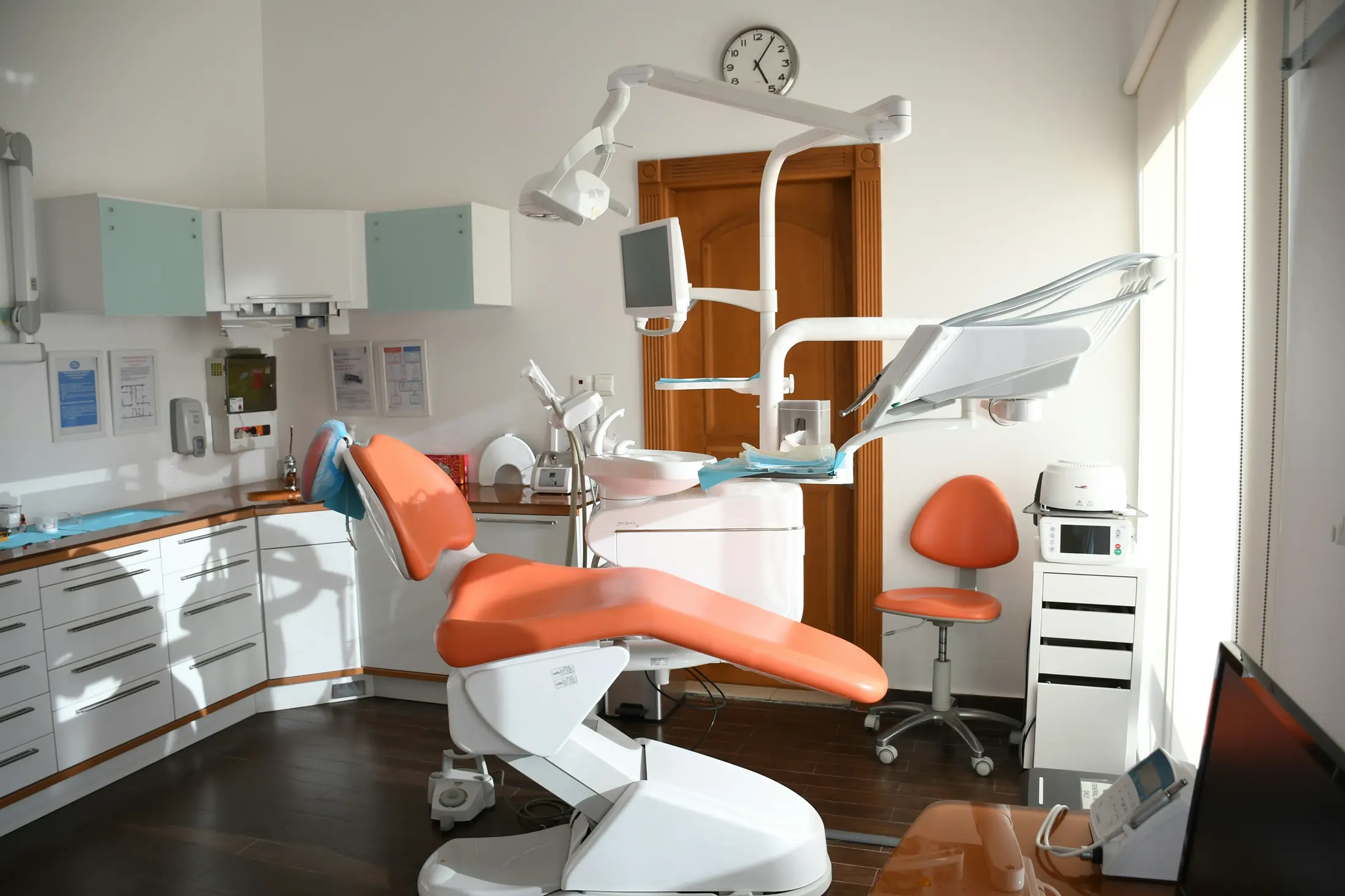 Tannlegekontor med oransje behandlingsstol og dentalutstyr.